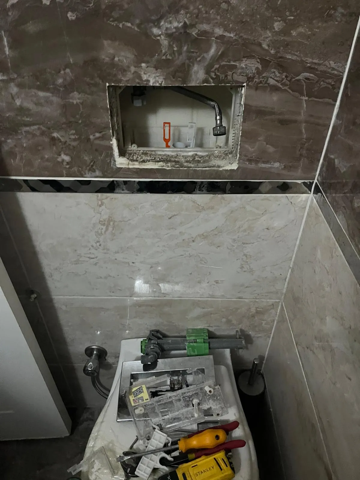 Servis kapağı açılmış gömme rezervuar ve sökülen parçalar